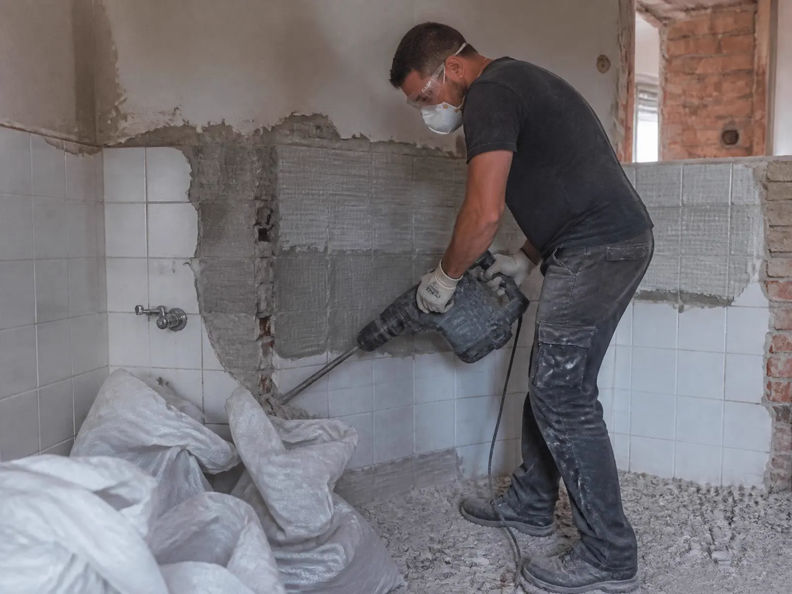 Remeselník búra staré obklady v kúpeľni pred rekonštrukciou